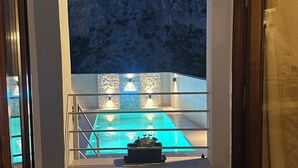 An indoor pool area with a view of a mountainous landscape through an arched opening.