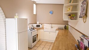Cocina compacta con electrodomésticos blancos, un lavamanos y un ventanal pequeño.