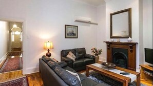 Una sala de estar con chimenea, sofá, mesa de centro y televisor.