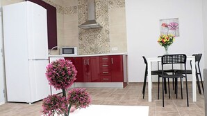 A compact kitchen with a white refrigerator, a microwave, and a red cabinet. There is a dining table with two chairs and a vase of flowers. - Rural house near Conil with private pool (CONIL DE LA FRONTERA)