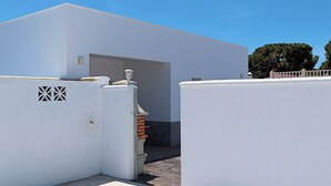 A modern building with a white exterior, a garage door, and a small brick structure. - Rural house near Conil with private pool (CONIL DE LA FRONTERA)