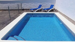 A rectangular pool with a tiled edge, two blue lounge chairs, and a metal fence. - Rural house near Conil with private pool (CONIL DE LA FRONTERA)