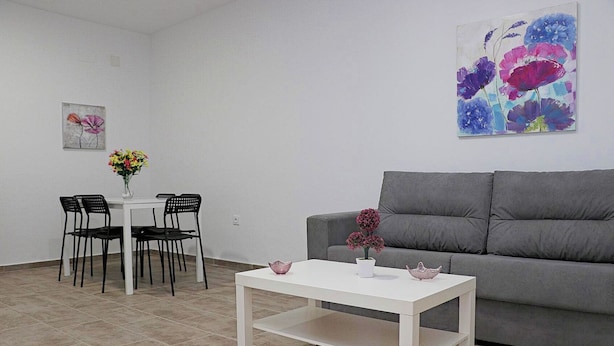 A modern living room with a grey sofa, a white coffee table, and a dining area with a white table and black chairs. - Rural house near Conil with private pool (CONIL DE LA FRONTERA)