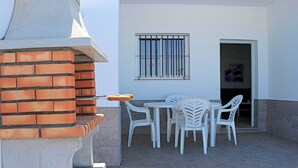 An outdoor patio with a brick grill, white plastic chairs, and a table. - Rural house near Conil with private pool (CONIL DE LA FRONTERA)