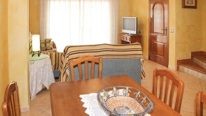 Une chambre d’hôtel comprenant un lit, une télévision, une table à manger avec des chaises, une petite table avec une lampe et une porte.