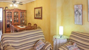 Un salon avec des canapés à rayures, un meuble en bois, une table à manger et un ventilateur de plafond.