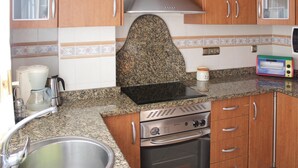 Une cuisine dotée de plans de travail en granit, d’appareils électroménagers en acier inoxydable et d’armoires en bois.