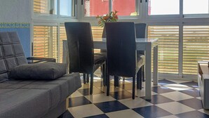 Una sala de estar moderna con piso a cuadros, un sofá gris y un comedor con sillas y una mesa.
