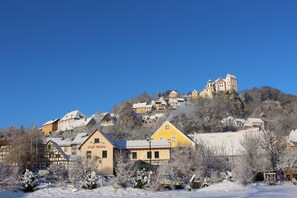 Eine Stadt mit schneebedeckten Gebäuden und einem Schloss auf einem Hügel.