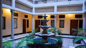 A courtyard with a central fountain, potted plants, and a multi-level balcony with intricate railings. - Hotel Arya Niwas, Jaipur (Jaipur)