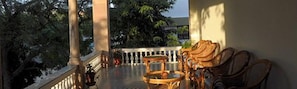 A balcony with wicker furniture, a railing, and trees in the background. - Hotel Arya Niwas, Jaipur (Jaipur)