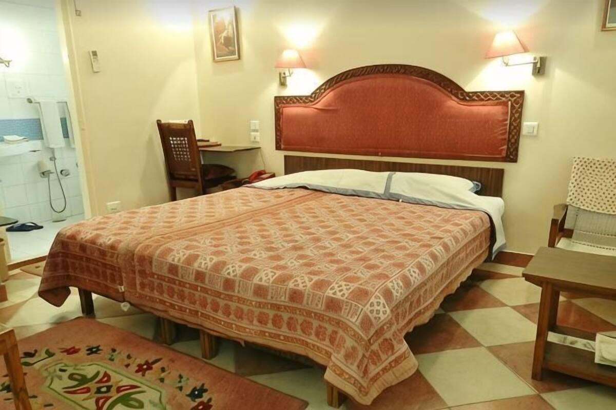 Ein Schlafzimmer mit Bett, Stuhl, Schreibtisch und Lampe.