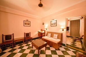 A room with a checkered floor, a sofa, a table, and two chairs. - Hotel Arya Niwas, Jaipur (Jaipur)