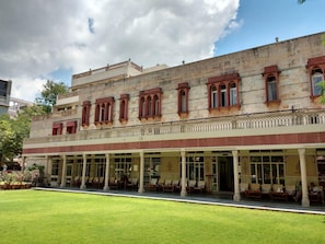 A historic building with a covered outdoor seating area and a well-maintained lawn. - Hotel Arya Niwas, Jaipur (Jaipur)