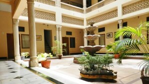 A spacious courtyard with a central fountain, multiple columns, and potted plants. - Hotel Arya Niwas, Jaipur (Jaipur)