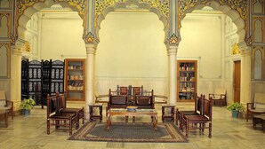 A traditional room with a sofa set, a coffee table, and a bookshelf. - Hotel Arya Niwas, Jaipur (Jaipur)
