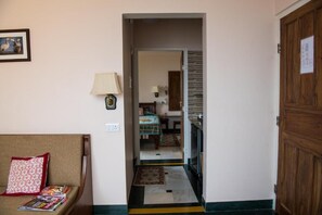 Un couloir menant à une chambre à coucher équipée d’un lit, d’une table de chevet et d’une lampe.