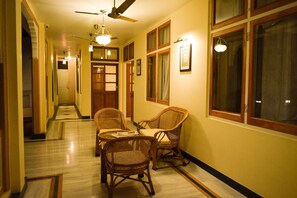 A hallway with wicker chairs, a ceiling fan, and a door at the end.