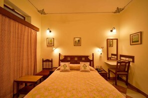 Une chambre à coucher comprenant un lit, des tables de chevet, un bureau, une chaise et des lampes fixées au mur.