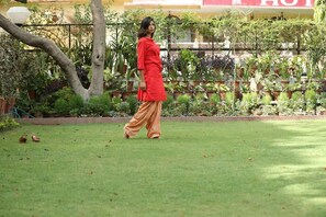 A person walking in a garden with potted plants and a building in the background. - Hotel Arya Niwas, Jaipur (Jaipur)