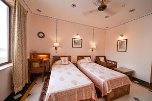 A room with two beds, a desk, a chair, and a window with curtains. - Hotel Arya Niwas, Jaipur (Jaipur)
