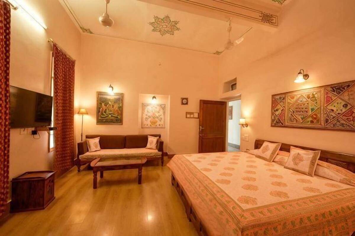 Ein Hotelzimmer mit Bett, Sofa, Fernseher und Bildern an den Wänden.