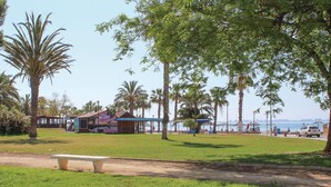 Un parque con césped, bancos, palmeras y un edificio con un mural.