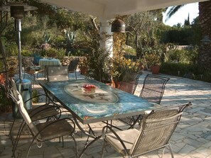 An outdoor patio with a table and chairs, surrounded by potted plants and a stone floor. - Paradise (customer´s evaluation) (Lagoa)