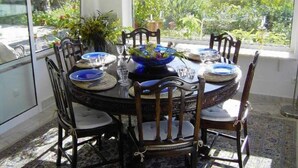 Une table à manger avec des assiettes bleues et un grand vase décoratif au centre, entourée de chaises en bois.