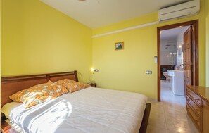 A bedroom with a bed, a nightstand, a lamp, and a small painting on the wall.
