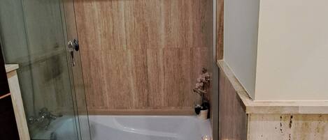 Un baño con ducha envuelta en vidrio, bañera y retrete.