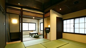 Een traditionele Japanse kamer met tatami vloerbedekking, een lage tafel met kussens en schuifdeuren.