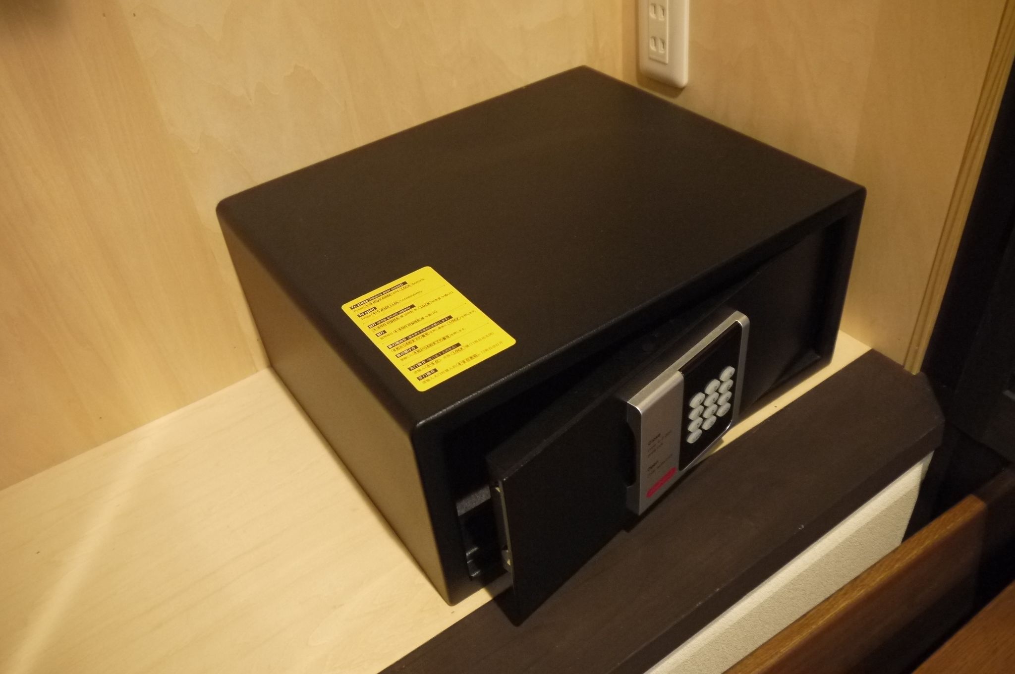 A black electronic device with a yellow label on a wooden surface.