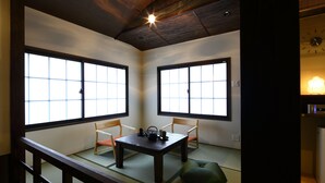 Een traditionele Japanse kamer met tatami vloerbedekking, een lage tafel met theeservies en schuifdeuren.