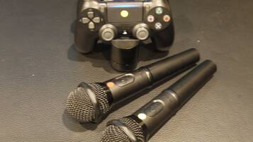 A black game controller and two microphones on a textured surface.
