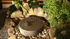Een traditionele Japanse tuin met een stenen lantaarn, bamboe en een klein vijvertje.