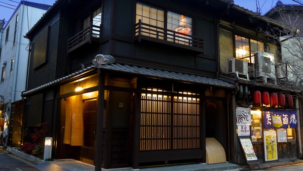 Een traditioneel Japans gebouw met een houten gevel, pannendak en een klein balkon.