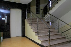 A staircase with metal railings and a carpeted floor leading to a door. - Natna Hotel (Addis Ababa)