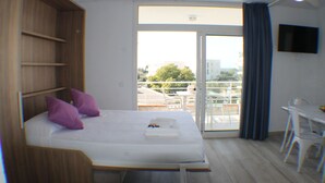A bedroom with a bed, a desk, and a balcony. - Rescator Resort 330 - One Bedroom Apartment, Sleeps 4 (Roses)