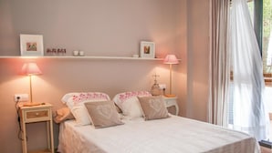 A bedroom with a bed, bedside tables, a lamp, and a window with curtains. - Lovely apartment in Alcossebre (Alcossebre)