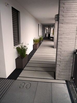A corridor with a tiled floor, potted plants, and a security camera.