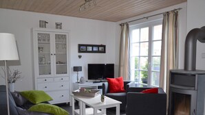 Ein modernes Wohnzimmer mit Kamin, grauen Sofas, einer weißen Kommode und einem Fernseher.
