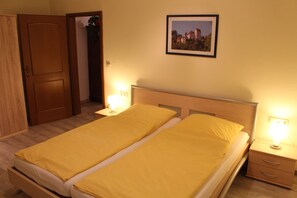 Una cama doble con dos mesitas de noche, cada una con una lámpara, un cuadro en la pared y un armario de madera.