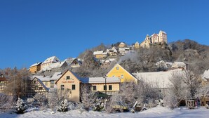 A town with snow-covered buildings and a castle on a hill. - Category C: 3-room apartment for 4 persons - Pension Mühle (Egloffstein)