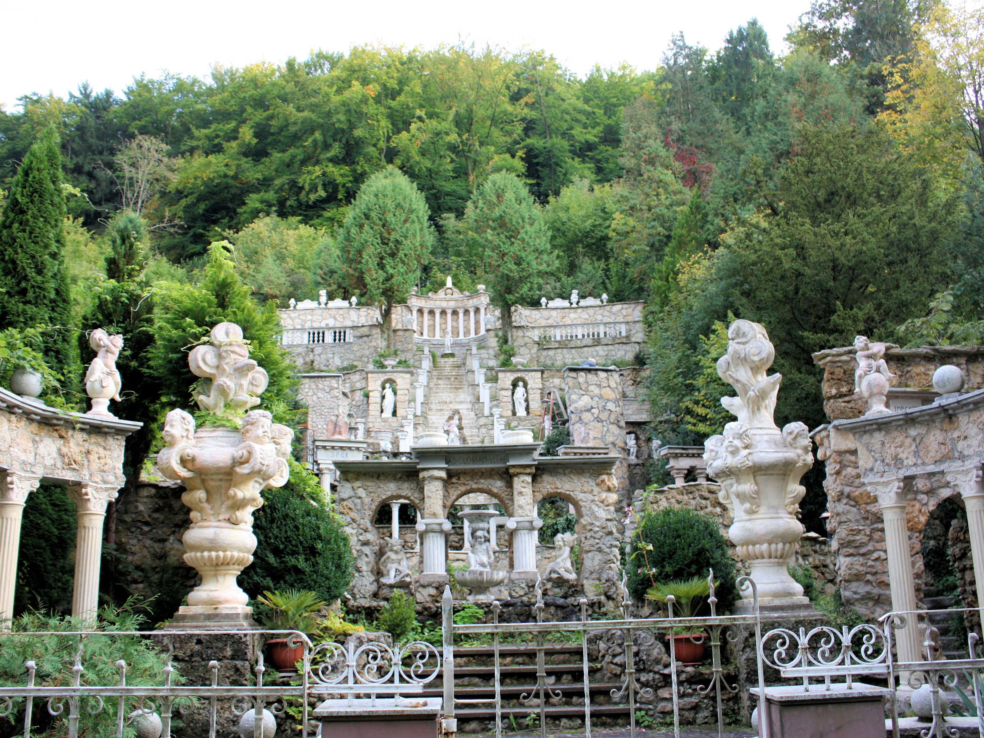 Ein Gebäude aus Stein mit klassischer Architektur, umgeben von üppigem Grün.