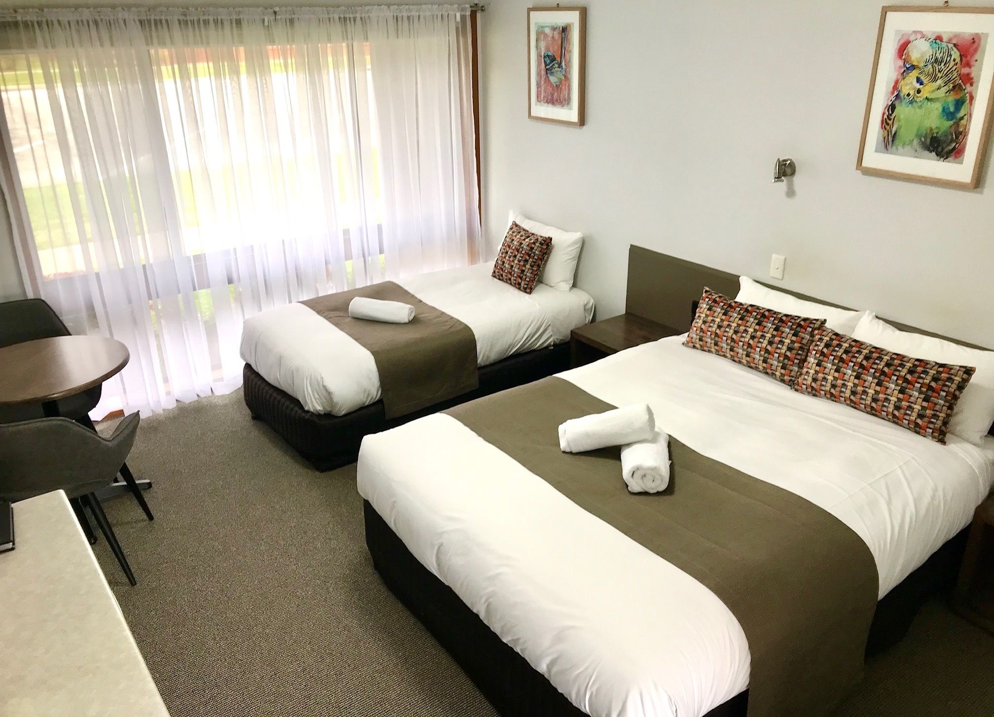 A hotel room with two beds, a desk, and a chair.