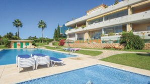 Zona piscina con lettini e un edificio con balconi.