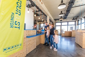 Un espace d’accueil doté d’un comptoir en bois, de luminaires suspendus et d’une grande banderole jaune avec du texte.