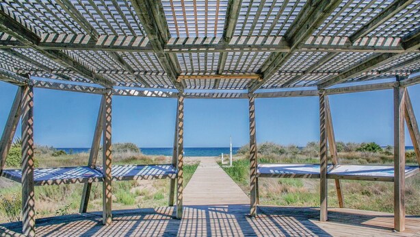 Una pérgola de madera con vista al océano.