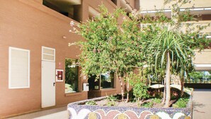 Un edificio con una jardinera de azulejos que contiene varias plantas y una palmera.